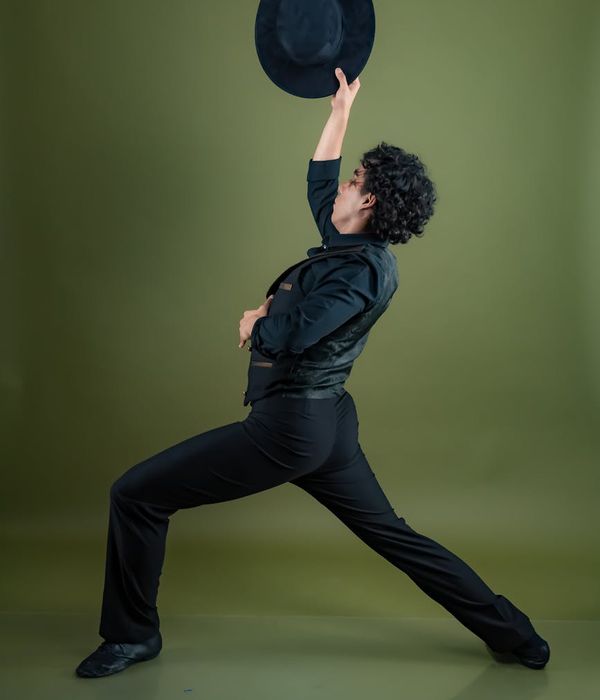 Person performing a gentle, energetic movement in a dark studio.